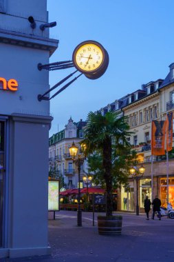 Baden-Baden, Almanya - 13 Ekim 2024: Baden-Baden, Baden-Wurttemberg, Almanya 'da çeşitli binalar, yerliler ve ziyaretçilerle birlikte günbatımı sokak manzarası