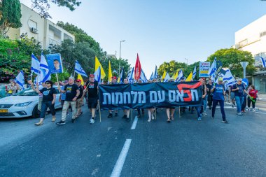 Hayfa, İsrail - 28 Haziran 2025: Çeşitli tabelaları ve bayrakları olan insanlar, savaşın sona ermesi, rehine anlaşmasının tamamlanması ve yeni seçimlerin başlatılması için düzenlenen protesto mitingine katıldılar. Hayfa, İsrail