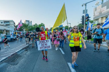 Hayfa, İsrail - 28 Haziran 2025: Çeşitli tabelaları ve bayrakları olan insanlar, savaşın sona ermesi, rehine anlaşmasının tamamlanması ve yeni seçimlerin başlatılması için düzenlenen protesto mitingine katıldılar. Hayfa, İsrail