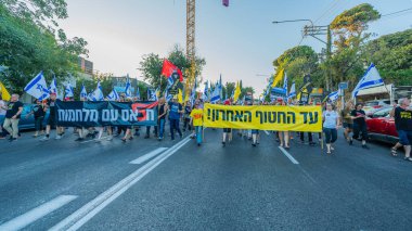 Hayfa, İsrail - 28 Haziran 2025: Çeşitli tabelaları ve bayrakları olan insanlar, savaşın sona ermesi, rehine anlaşmasının tamamlanması ve yeni seçimlerin başlatılması için düzenlenen protesto mitingine katıldılar. Hayfa, İsrail
