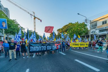 Hayfa, İsrail - 28 Haziran 2025: Çeşitli tabelaları ve bayrakları olan insanlar, savaşın sona ermesi, rehine anlaşmasının tamamlanması ve yeni seçimlerin başlatılması için düzenlenen protesto mitingine katıldılar. Hayfa, İsrail