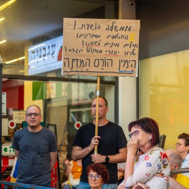 Hayfa, İsrail - 28 Haziran 2025: Çeşitli tabela ve bayraklara sahip bir grup insan, savaşın sona ermesi, rehine anlaşmasının tamamlanması ve yeni seçimler için düzenlenen protesto mitingine katıldı. Hayfa, İsrail