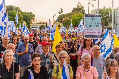 Hayfa, İsrail - 28 Haziran 2025: Çeşitli tabela ve bayraklara sahip bir grup insan, savaşın sona ermesi, rehine anlaşmasının tamamlanması ve yeni seçimler için düzenlenen protesto mitingine katıldı. Hayfa, İsrail