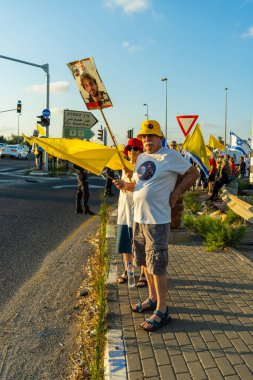 Ein HaMifratz, İsrail - 3 Temmuz 2025: Rehine posterleri ve diğer tabelaları olan insanlar, otoyolun yakınında, rehinelere destek çağrısında bulunuyorlar ve anlaşmanın tamamlanmasını istiyorlar, Ein HaMifratz, İsrail