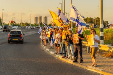 Ein HaMifratz, İsrail - 3 Temmuz 2025: Rehine posterleri ve diğer tabelaları olan insanlar, otoyolun yakınında, rehinelere destek çağrısında bulunuyorlar ve anlaşmanın tamamlanmasını istiyorlar, Ein HaMifratz, İsrail