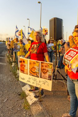 Ein HaMifratz, İsrail - 3 Temmuz 2025: Rehine posterleri ve diğer tabelaları olan insanlar, otoyolun yakınında, rehinelere destek çağrısında bulunuyorlar ve anlaşmanın tamamlanmasını istiyorlar, Ein HaMifratz, İsrail