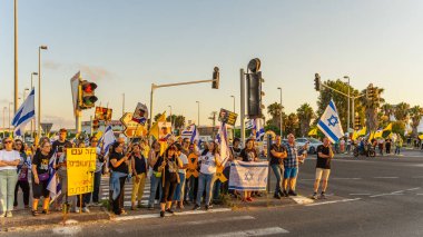 Ein HaMifratz, İsrail - 3 Temmuz 2025: Rehine posterleri ve diğer tabelaları olan insanlar, otoyolun yakınında, rehinelere destek çağrısında bulunuyorlar ve anlaşmanın tamamlanmasını istiyorlar, Ein HaMifratz, İsrail