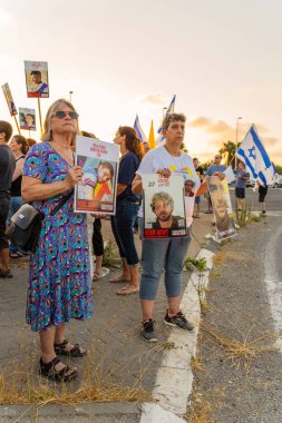Ein HaMifratz, İsrail - 3 Temmuz 2025: Rehine posterleri ve diğer tabelaları olan insanlar, otoyolun yakınında, rehinelere destek çağrısında bulunuyorlar ve anlaşmanın tamamlanmasını istiyorlar, Ein HaMifratz, İsrail