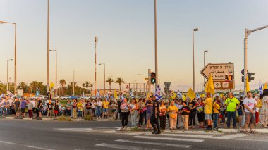 Ein HaMifratz, İsrail - 3 Temmuz 2025: Rehine posterleri ve diğer tabelaları olan insanlar, otoyolun yakınında, rehinelere destek çağrısında bulunuyorlar ve anlaşmanın tamamlanmasını istiyorlar, Ein HaMifratz, İsrail