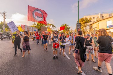 Hayfa, İsrail - 12 Temmuz 2025: İnsanlar çeşitli işaret ve bayraklarla bir protesto yürüyüşüne katılıyor, savaşın sona ermesi ve rehine anlaşmasının tamamlanması çağrısında bulunuyorlar. Hayfa, İsrail