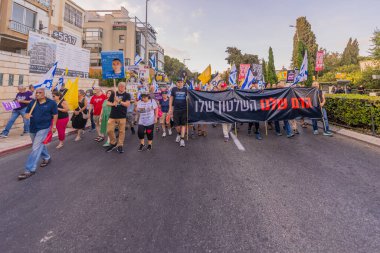 Hayfa, İsrail - 12 Temmuz 2025: Çeşitli tabelaları ve bayrakları olan insanlar, savaşın sona ermesi, rehine anlaşmasının tamamlanması ve yeni seçimlerin başlatılması için düzenlenen protesto mitingine katıldılar. Hayfa, İsrail
