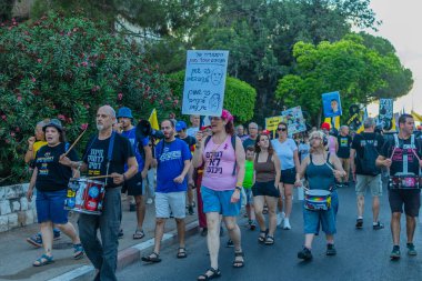 Hayfa, İsrail - 12 Temmuz 2025: Çeşitli tabelaları ve bayrakları olan insanlar, savaşın sona ermesi, rehine anlaşmasının tamamlanması ve yeni seçimlerin başlatılması için düzenlenen protesto mitingine katıldılar. Hayfa, İsrail