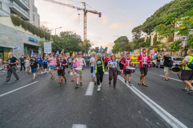 Hayfa, İsrail - 12 Temmuz 2025: İnsanlar savaşın sona ermesi, rehine anlaşmasının tamamlanması ve yeni seçimler çağrısında bulunan bir protesto yürüyüşüne (Pembe Cephe Grubu) katılıyor. Hayfa, İsrail
