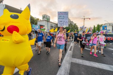 Hayfa, İsrail - 12 Temmuz 2025: İnsanlar (Pikachu kostümlü adamla birlikte) savaşın sona ermesi, rehine anlaşmasının tamamlanması ve yeni seçimler çağrısında bulunan bir protesto yürüyüşüne katılıyor. Hayfa, İsrail