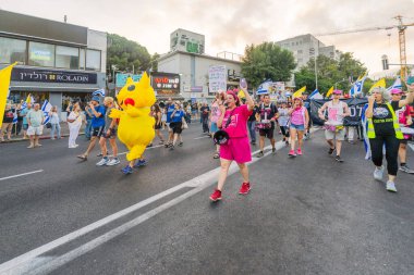 Hayfa, İsrail - 12 Temmuz 2025: İnsanlar (Pikachu kostümlü adamla birlikte) savaşın sona ermesi, rehine anlaşmasının tamamlanması ve yeni seçimler çağrısında bulunan bir protesto yürüyüşüne katılıyor. Hayfa, İsrail