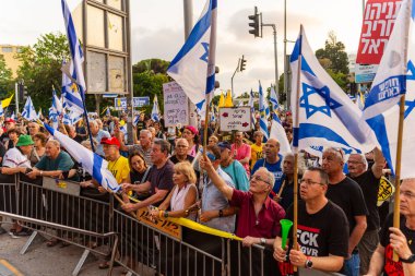 Hayfa, İsrail - 12 Temmuz 2025: Çeşitli tabela ve bayraklara sahip bir grup insan, savaşın sona ermesi, rehine anlaşmasının tamamlanması ve yeni seçimler için düzenlenen protesto mitingine katıldı. Hayfa, İsrail