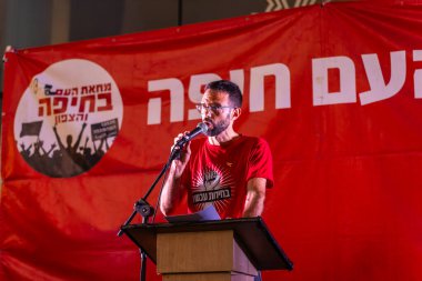 Hayfa, İsrail - 12 Temmuz 2025: Dr. Nir Barak, savaşın sona ermesi, rehine anlaşmasının tamamlanması ve yeni seçimler için düzenlenen protesto mitinginin bir parçası olarak kalabalığa sesleniyor. Hayfa, İsrail