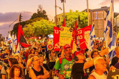 Hayfa, İsrail - 12 Temmuz 2025: Çeşitli tabela ve bayraklara sahip bir grup insan, savaşın sona ermesi, rehine anlaşmasının tamamlanması ve yeni seçimler için düzenlenen protesto mitingine katıldı. Hayfa, İsrail