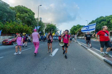 Hayfa, İsrail - 19 Temmuz 2025: İnsanlar savaşın sona ermesi, rehine anlaşmasının tamamlanması ve yeni seçimler çağrısında bulunan bir protesto yürüyüşüne (Pembe Cephe Grubu) katılıyor. Hayfa, İsrail