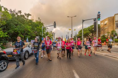 Hayfa, İsrail - 19 Temmuz 2025: İnsanlar savaşın sona ermesi, rehine anlaşmasının tamamlanması ve yeni seçimler çağrısında bulunan bir protesto yürüyüşüne (Pembe Cephe Grubu) katılıyor. Hayfa, İsrail
