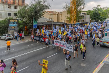 Hayfa, İsrail - 19 Temmuz 2025: Çeşitli tabelaları ve bayrakları olan insanlar, savaşın sona ermesi, rehine anlaşmasının tamamlanması ve yeni seçimlerin başlatılması için düzenlenen protesto mitingine katıldılar. Hayfa, İsrail