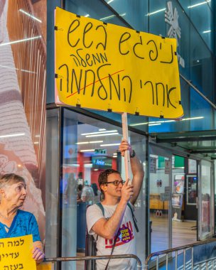 Hayfa, İsrail - 19 Temmuz 2025: Çeşitli tabela ve bayraklara sahip bir grup insan, savaşın sona ermesi, rehine anlaşmasının tamamlanması ve yeni seçimler için düzenlenen protesto mitingine katıldı. Hayfa, İsrail