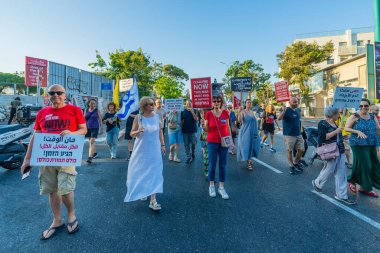 Hayfa, İsrail - 26 Temmuz 2025: İnsanlar çeşitli işaret ve bayraklarla bir protesto yürüyüşüne katılıyor, savaşın sona ermesi ve rehine anlaşmasının tamamlanması çağrısında bulunuyorlar. Hayfa, İsrail