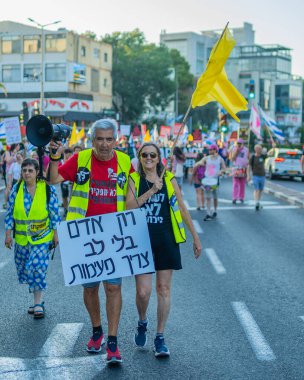 Hayfa, İsrail - 26 Temmuz 2025: Çeşitli tabela ve bayraklara sahip kişiler, savaşın sona ermesi, rehine anlaşmasının tamamlanması ve yeni seçimlerin başlatılması için düzenlenen protesto mitingine katıldılar. Hayfa, İsrail