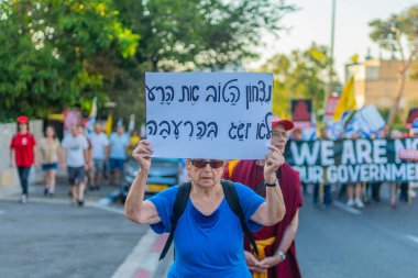 Hayfa, İsrail - 26 Temmuz 2025: Çeşitli tabela ve bayraklara sahip kişiler, savaşın sona ermesi, rehine anlaşmasının tamamlanması ve yeni seçimlerin başlatılması için düzenlenen protesto mitingine katıldılar. Hayfa, İsrail