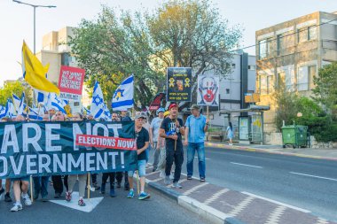 Hayfa, İsrail - 26 Temmuz 2025: Çeşitli tabela ve bayraklara sahip kişiler, savaşın sona ermesi, rehine anlaşmasının tamamlanması ve yeni seçimlerin başlatılması için düzenlenen protesto mitingine katıldılar. Hayfa, İsrail