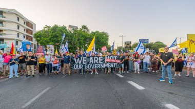 Hayfa, İsrail - 26 Temmuz 2025: Çeşitli tabela ve bayraklara sahip kişiler, savaşın sona ermesi, rehine anlaşmasının tamamlanması ve yeni seçimlerin başlatılması için düzenlenen protesto mitingine katıldılar. Hayfa, İsrail