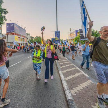 Hayfa, İsrail - 26 Temmuz 2025: Çeşitli tabela ve bayraklara sahip kişiler, savaşın sona ermesi, rehine anlaşmasının tamamlanması ve yeni seçimlerin başlatılması için düzenlenen protesto mitingine katıldılar. Hayfa, İsrail