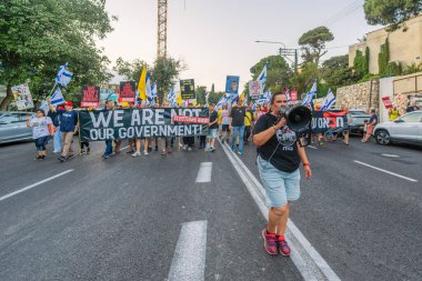 Hayfa, İsrail - 26 Temmuz 2025: Çeşitli tabela ve bayraklara sahip kişiler, savaşın sona ermesi, rehine anlaşmasının tamamlanması ve yeni seçimlerin başlatılması için düzenlenen protesto mitingine katıldılar. Hayfa, İsrail