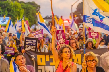 Hayfa, İsrail - 26 Temmuz 2025: Çeşitli tabela ve bayraklara sahip bir grup insan, savaşın sona ermesi, rehine anlaşmasının tamamlanması ve yeni seçimler için düzenlenen protesto mitingine katıldı. Hayfa, İsrail