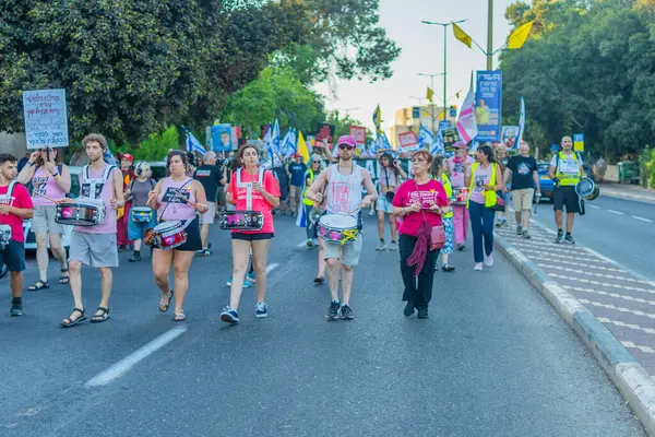 Hayfa, İsrail - 26 Temmuz 2025: İnsanlar savaşın sona ermesi, rehine anlaşmasının tamamlanması ve yeni seçimler çağrısında bulunan bir protesto yürüyüşüne (Pembe Cephe Grubu) katılıyor. Hayfa, İsrail
