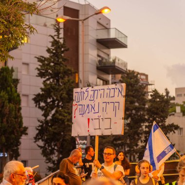 Hayfa, İsrail - 2 Ağustos 2025: Çeşitli tabela ve bayraklara sahip bir grup insan, savaşın sona ermesi, rehine anlaşmasının tamamlanması ve yeni seçimler için düzenlenen protesto mitingine katıldı. Hayfa, İsrail