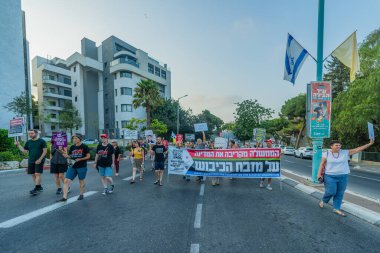 Hayfa, İsrail - 09 Ağustos 2025: İnsanlar çeşitli işaret ve bayraklarla bir protesto yürüyüşüne katılıyor, savaşı sona erdirme ve rehine anlaşmasının tamamlanması çağrısında bulunuyorlar. Hayfa, İsrail