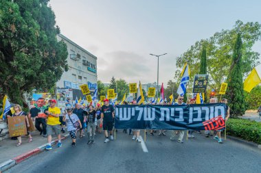 Hayfa, İsrail - 09 Ağustos 2025: Çeşitli tabelaları ve bayrakları olan insanlar, savaşın sona ermesi, rehine anlaşmasının tamamlanması ve yeni seçimlerin başlatılması için düzenlenen protesto mitingine katıldılar. Hayfa, İsrail