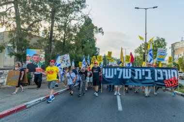 Hayfa, İsrail - 09 Ağustos 2025: Çeşitli tabelaları ve bayrakları olan insanlar, savaşın sona ermesi, rehine anlaşmasının tamamlanması ve yeni seçimlerin başlatılması için düzenlenen protesto mitingine katıldılar. Hayfa, İsrail