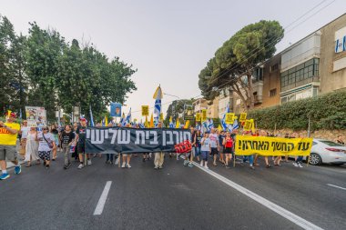 Hayfa, İsrail - 09 Ağustos 2025: Çeşitli tabelaları ve bayrakları olan insanlar, savaşın sona ermesi, rehine anlaşmasının tamamlanması ve yeni seçimlerin başlatılması için düzenlenen protesto mitingine katıldılar. Hayfa, İsrail