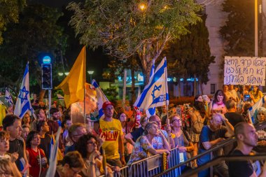 Hayfa, İsrail - 09 Ağustos 2025: Çeşitli tabela ve bayraklara sahip bir grup insan, savaşın sona ermesi, rehine anlaşmasının tamamlanması ve yeni seçimler için düzenlenen protesto mitingine katıldı. Hayfa, İsrail