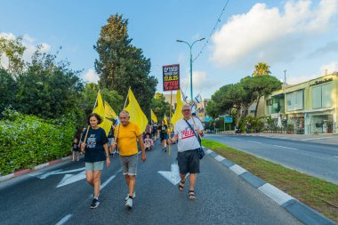 Hayfa, İsrail - 16 Ağustos 2025: Çeşitli tabelaları ve bayrakları olan insanlar, savaşın sona ermesi, rehine anlaşmasının tamamlanması ve yeni seçimlerin başlatılması için düzenlenen protesto mitingine katıldılar. Hayfa, İsrail