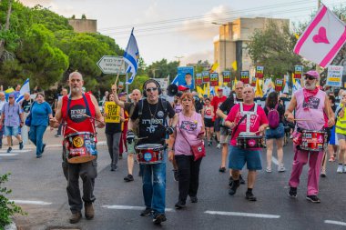 Hayfa, İsrail - 16 Ağustos 2025: İnsanlar savaşın sona ermesi, rehine anlaşmasının tamamlanması ve yeni seçimler çağrısında bulunan bir protesto yürüyüşüne (Pembe Cephe Grubu) katılıyor. Hayfa, İsrail