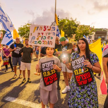 Hayfa, İsrail - 16 Ağustos 2025: Çeşitli tabela ve bayraklara sahip bir grup insan, savaşın sona ermesi, rehine anlaşmasının tamamlanması ve yeni seçimler için düzenlenen protesto mitingine katıldı. Hayfa, İsrail