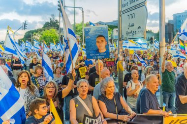 Hayfa, İsrail - 16 Ağustos 2025: Çeşitli tabela ve bayraklara sahip bir grup insan, savaşın sona ermesi, rehine anlaşmasının tamamlanması ve yeni seçimler için düzenlenen protesto mitingine katıldı. Hayfa, İsrail