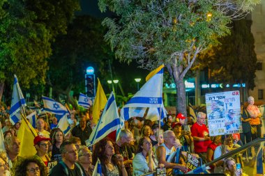 Hayfa, İsrail - 16 Ağustos 2025: Çeşitli tabela ve bayraklara sahip bir grup insan, savaşın sona ermesi, rehine anlaşmasının tamamlanması ve yeni seçimler için düzenlenen protesto mitingine katıldı. Hayfa, İsrail