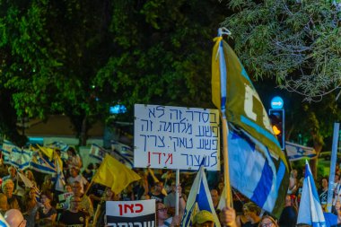 Hayfa, İsrail - 16 Ağustos 2025: Çeşitli tabela ve bayraklara sahip bir grup insan, savaşın sona ermesi, rehine anlaşmasının tamamlanması ve yeni seçimler için düzenlenen protesto mitingine katıldı. Hayfa, İsrail