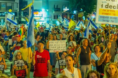 Hayfa, İsrail - 16 Ağustos 2025: Çeşitli tabela ve bayraklara sahip bir grup insan, savaşın sona ermesi, rehine anlaşmasının tamamlanması ve yeni seçimler için düzenlenen protesto mitingine katıldı. Hayfa, İsrail