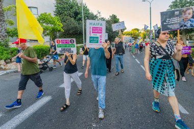 Hayfa, İsrail - 23 Ağustos 2025: İnsanlar çeşitli işaret ve bayraklarla bir protesto yürüyüşüne katılıyor, savaşın sona ermesi ve rehine anlaşmasının tamamlanması çağrısında bulunuyorlar. Hayfa, İsrail