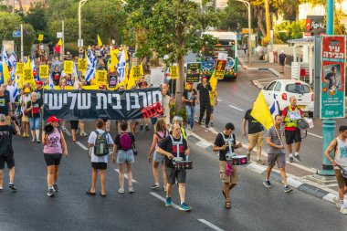 Hayfa, İsrail - 23 Ağustos 2025: Çeşitli tabelaları ve bayrakları olan insanlar, savaşın sona ermesi, rehine anlaşmasının tamamlanması ve yeni seçimler için düzenlenen protesto mitingine katıldılar. Hayfa, İsrail